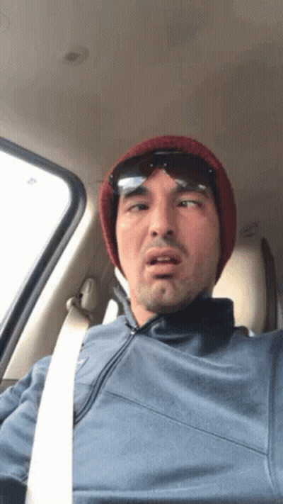 A Man Wearing A Beanie And Sunglasses Is Sitting In The Driver 'S Seat Of A Car GIF