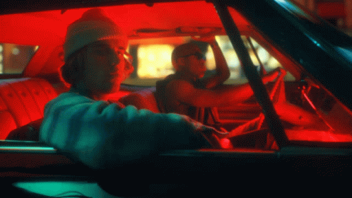 A Man Wearing A Beanie Is Driving A Car With A Red Roof GIF
