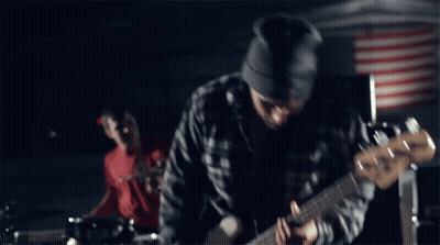 A Man Wearing A Beanie Is Playing A Guitar GIF