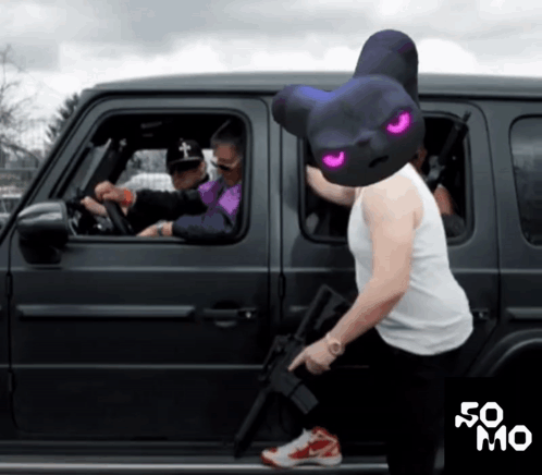 A Man Wearing A Bear Mask Holds A Gun In Front Of A Black Car GIF