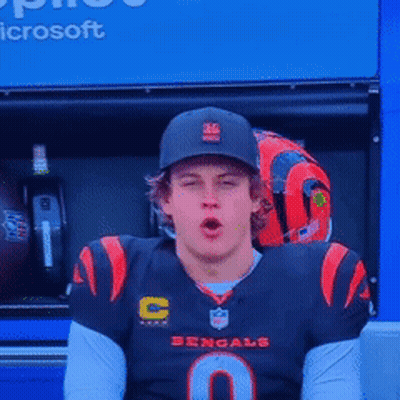 A Man Wearing A Bengals Jersey Is Sitting In Front Of A Microsoft Advertisement GIF