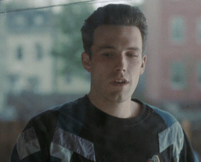 A Man Wearing A Black And Blue Sweater With A Logo On It GIF