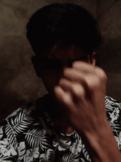 A Man Wearing A Black And White Floral Shirt Looks Down GIF
