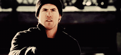 A Man Wearing A Black Beanie And A Black Jacket Is Pointing At The Camera GIF