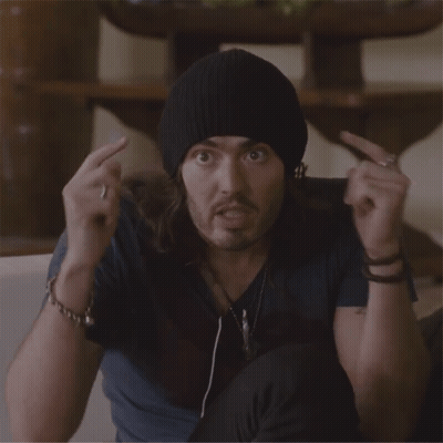 A Man Wearing A Black Beanie Is Making A Surprised Face With His Hands In The Air GIF