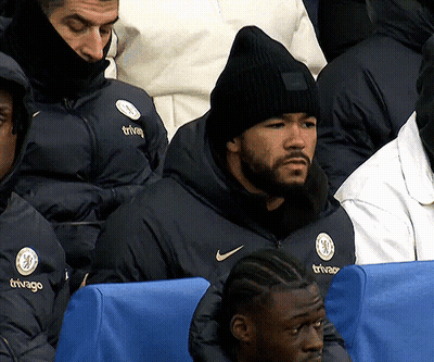 A Man Wearing A Black Beanie Is Sitting In A Stadium Watching A Game GIF