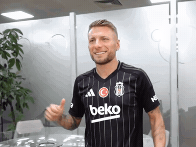 A Man Wearing A Black Beko Shirt Is Giving A Thumbs Up GIF