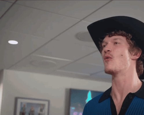 A Man Wearing A Black Cowboy Hat And A Blue Shirt GIF