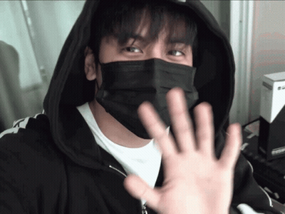 A Man Wearing A Black Face Mask And A Black Hoodie Is Waving GIF