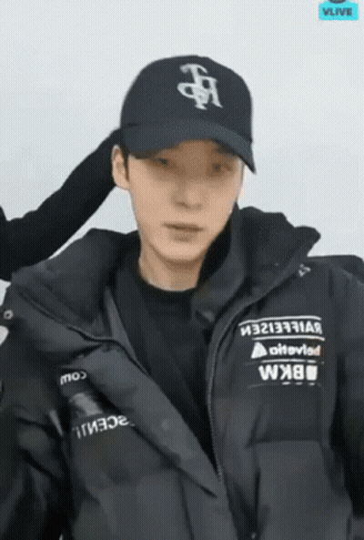 A Man Wearing A Black Hat And A Black Jacket Is Looking At The Camera . GIF