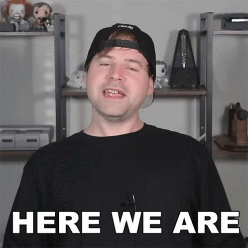 A Man Wearing A Black Hat And A Black Shirt Says Here We Are GIF