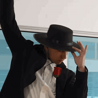 A Man Wearing A Black Hat And A Rose In His Pocket GIF