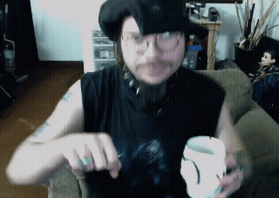 A Man Wearing A Black Hat And Glasses Is Holding A White Cup GIF