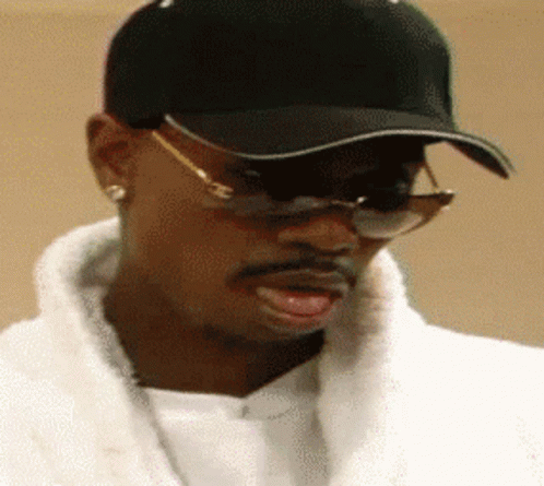 A Man Wearing A Black Hat And Sunglasses Looks To His Left GIF