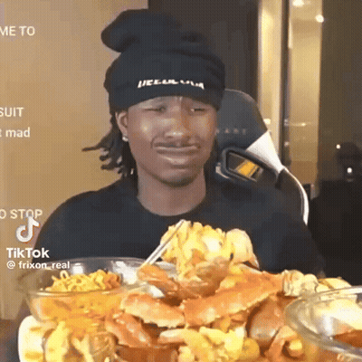 A Man Wearing A Black Hat Is Eating Crabs With Chopsticks .. GIF