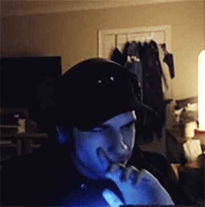 A Man Wearing A Black Hat Is Looking At A Computer Screen GIF