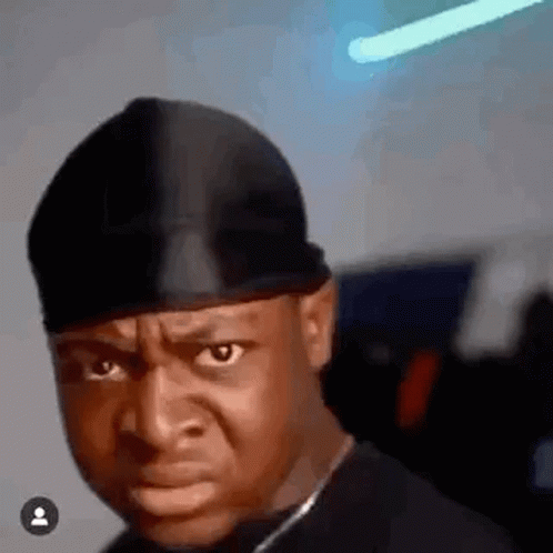 A Man Wearing A Black Hat Is Making A Funny Face And Looking At The Camera . GIF