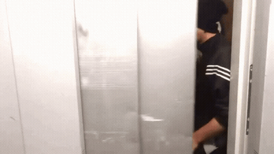 A Man Wearing A Black Hat Is Standing In A Doorway . GIF