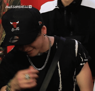 A Man Wearing A Black Hat With A Heart On It And A Chain Around His Neck Is Being Interviewed On Awesomeness Tv GIF