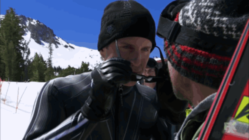 A Man Wearing A Black Hat With The Word Eagle On It Talks To Another Man GIF