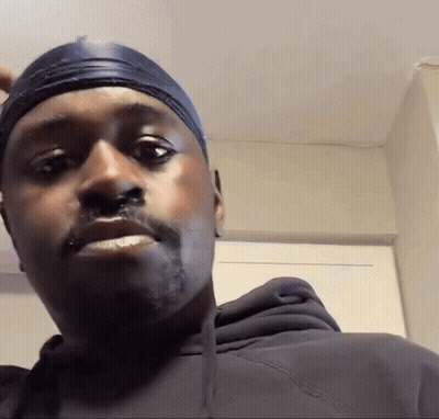 A Man Wearing A Black Hoodie And A Headband Looks At The Camera GIF