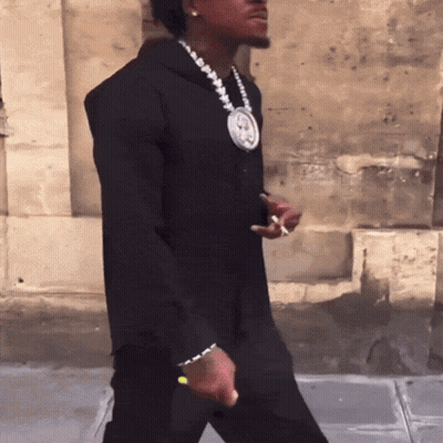 A Man Wearing A Black Hoodie And A Necklace With A Picture Of A Man On It GIF