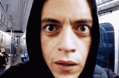 A Man Wearing A Black Hoodie Is Looking At The Camera With A Surprised Look On His Face GIF
