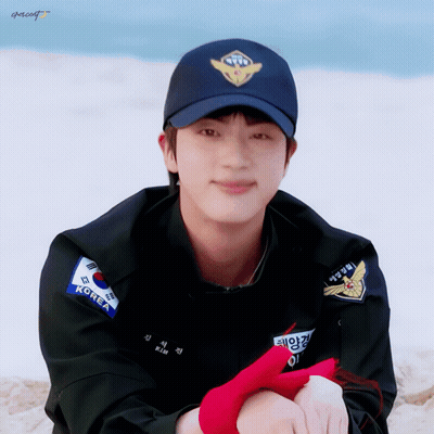 A Man Wearing A Black Jacket And A Blue Hat With The Word Korea On It GIF