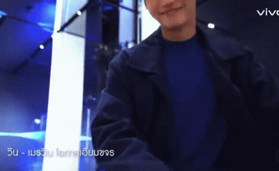 A Man Wearing A Black Jacket And A Blue Shirt Is Standing In A Room . GIF