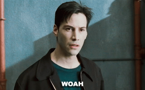 A Man Wearing A Black Jacket And A Green Sweater Has The Word Woah Above His Head GIF