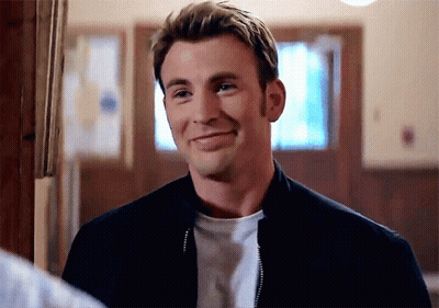 A Man Wearing A Black Jacket And A White Shirt Is Smiling In A Room . GIF