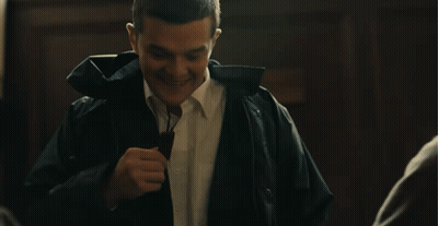 A Man Wearing A Black Jacket And A White Shirt Laughs GIF