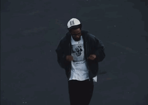 A Man Wearing A Black Jacket And A White Shirt With A Picture On It GIF