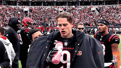 A Man Wearing A Black Jacket With The Number 9 On It Is Holding A Pink Water Bottle GIF