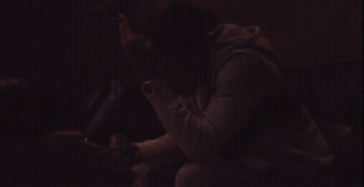 A Man Wearing A Black Jacket With The Word Rap On It Looks At His Cell Phone GIF