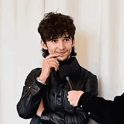 A Man Wearing A Black Leather Jacket Is Being Interviewed GIF
