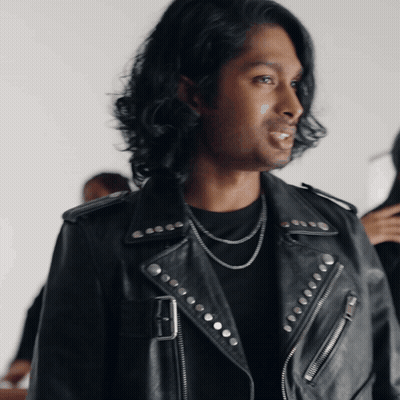 A Man Wearing A Black Leather Jacket With Studs On The Sleeves GIF