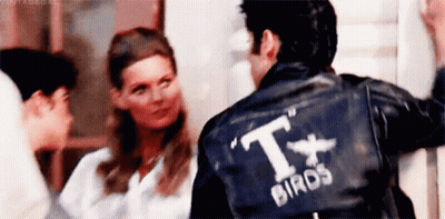 A Man Wearing A Black Leather Jacket With The Word Birds On The Back Is Standing Next To A Woman . GIF