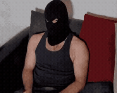 A Man Wearing A Black Mask Is Sitting On A Couch . GIF