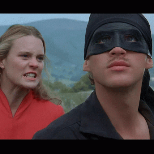 A Man Wearing A Black Mask Stands Next To A Woman Who Is Angry GIF