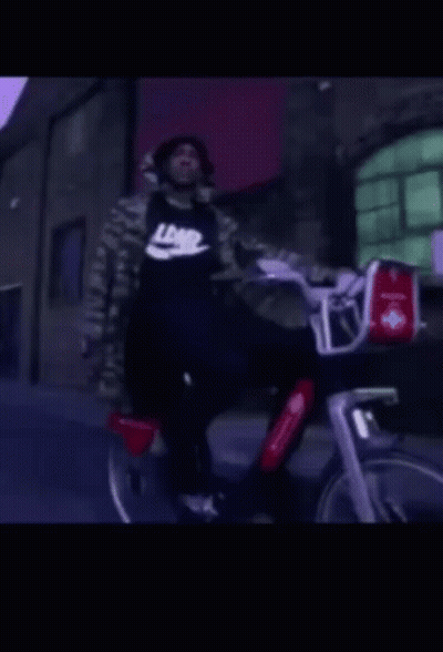 A Man Wearing A Black Nike Shirt Rides A Bike GIF