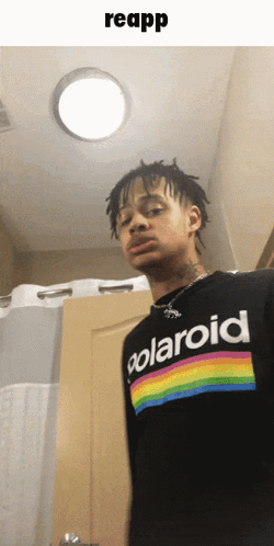 A Man Wearing A Black Polaroid Shirt Is Standing In A Bathroom GIF