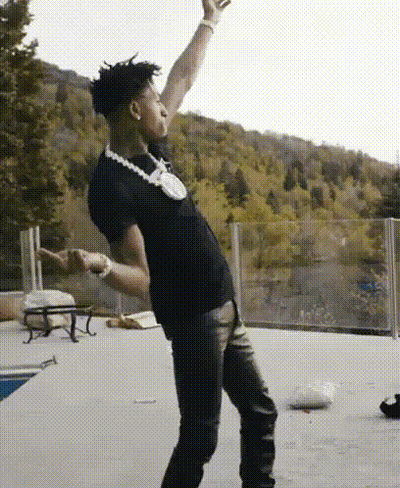 A Man Wearing A Black Shirt And A Necklace Is Dancing On A Patio . GIF