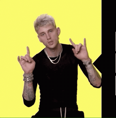 A Man Wearing A Black Shirt And A Silver Necklace Is Pointing At Something GIF