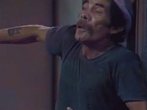 A Man Wearing A Black Shirt And A White Hat Looks Down GIF