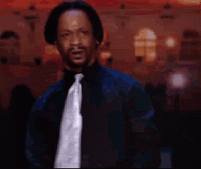 A Man Wearing A Black Shirt And Tie Is Standing In Front Of A Building GIF