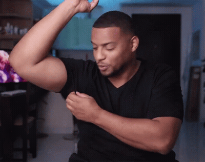 A Man Wearing A Black Shirt Is Flexing His Muscles GIF