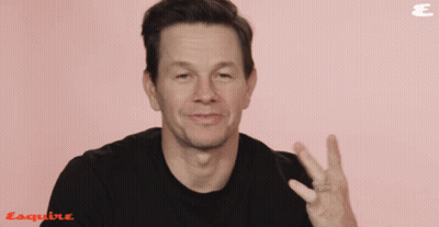 A Man Wearing A Black Shirt Is Giving A Peace Sign In Front Of An Esquire Logo GIF
