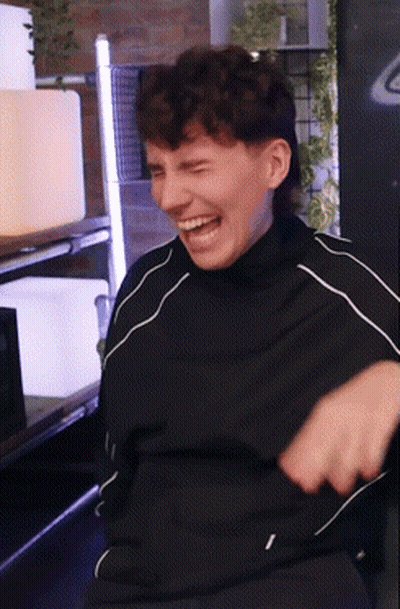 A Man Wearing A Black Shirt Is Laughing With His Mouth Open GIF