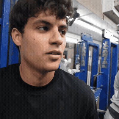 A Man Wearing A Black Shirt Stands In Front Of A Blue Door That Says ' A ' On It GIF